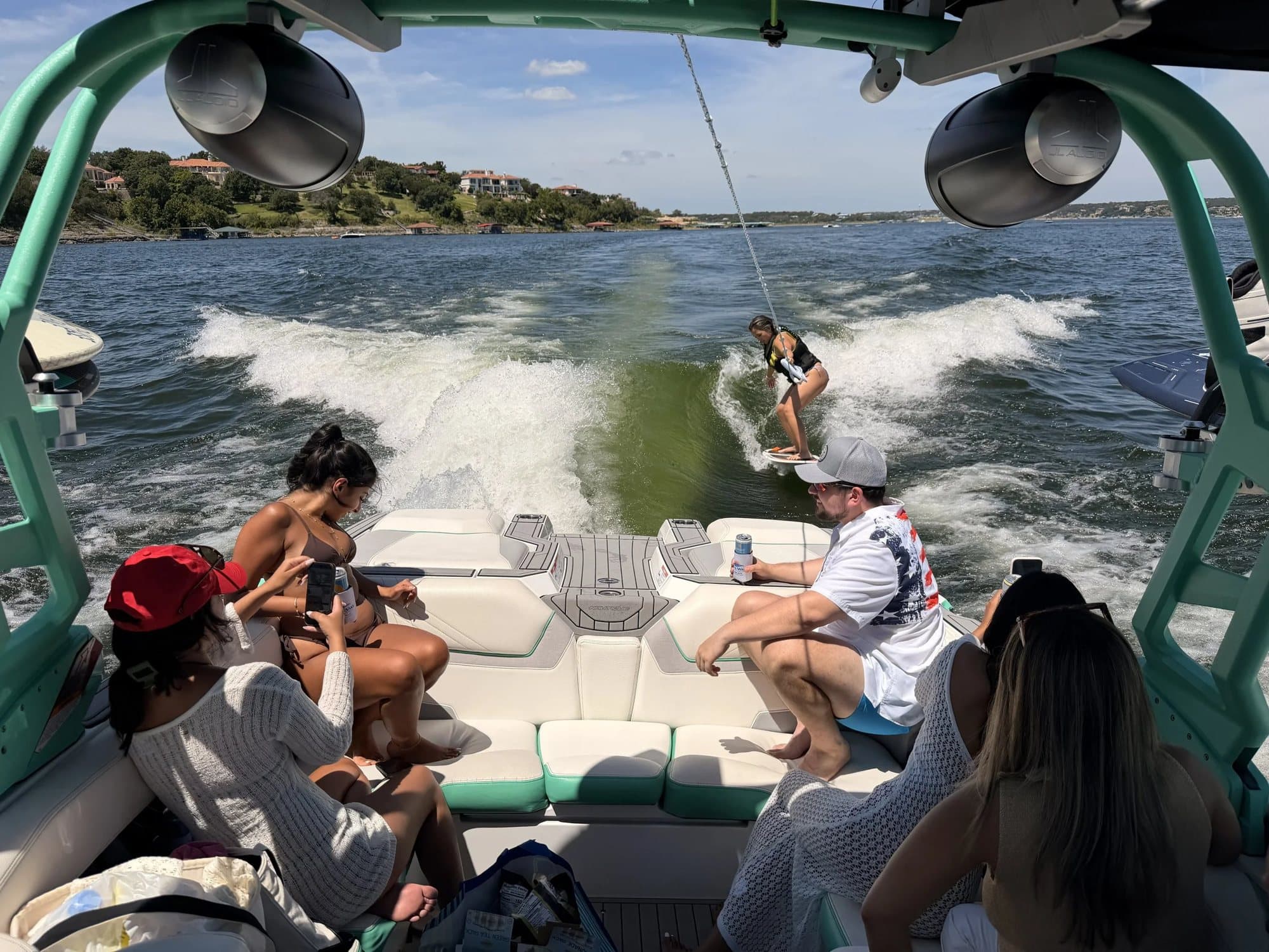 Guests aboard the Nautique watching a rider surf the wake.