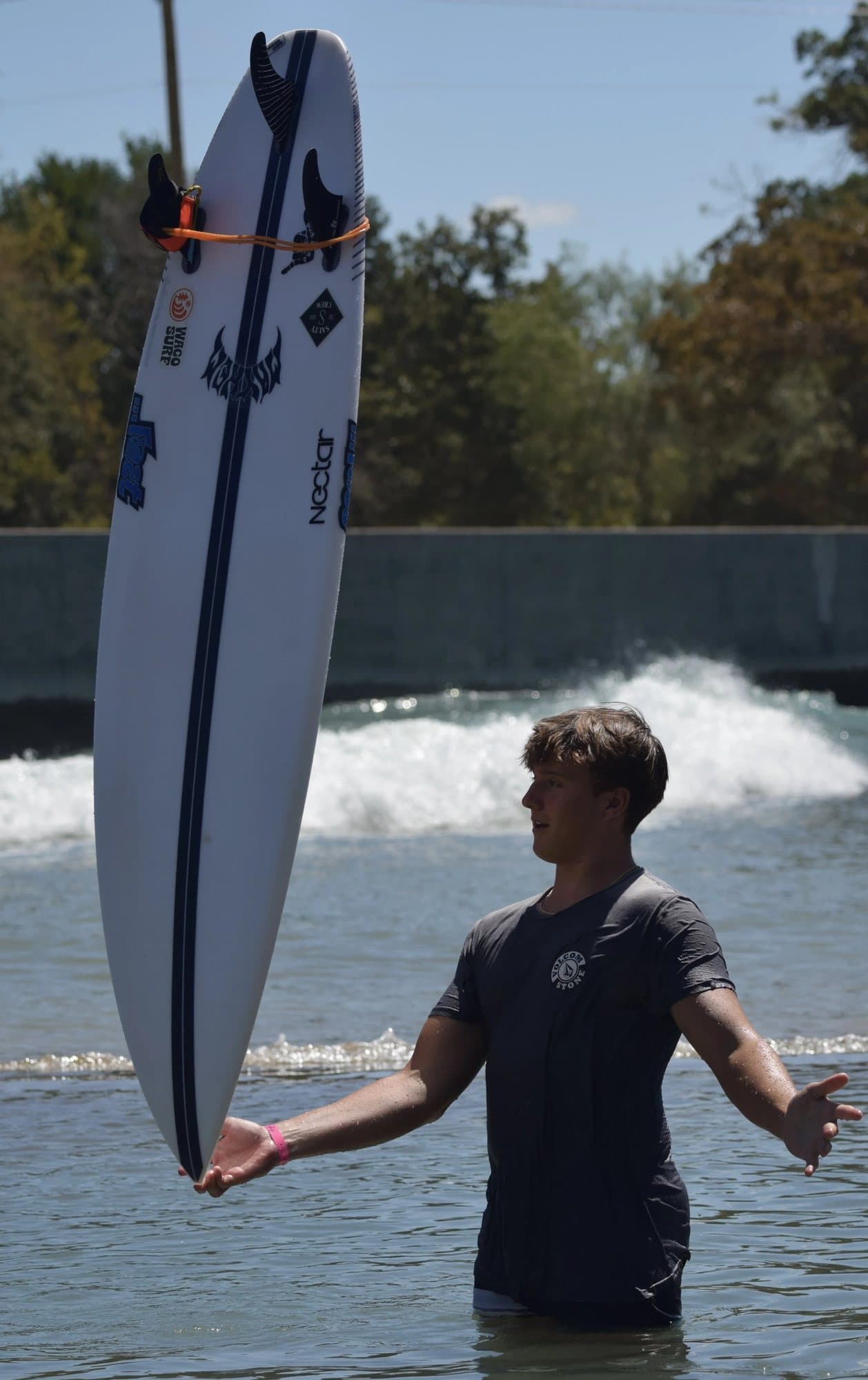 Jacob Jensen holding his surfboard at Waco Surf.