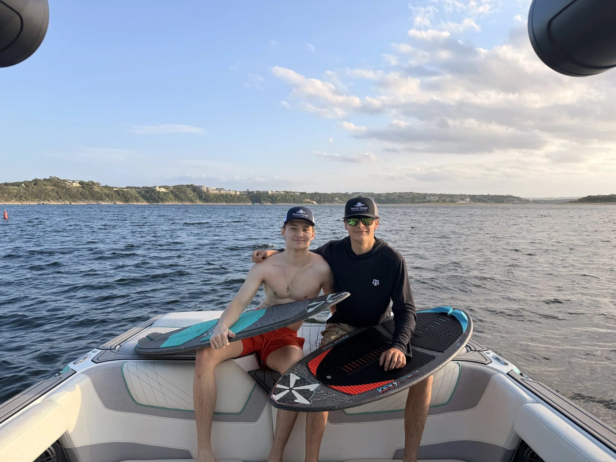 Two riders on the swim platform with a wakesurf board, ready to go.